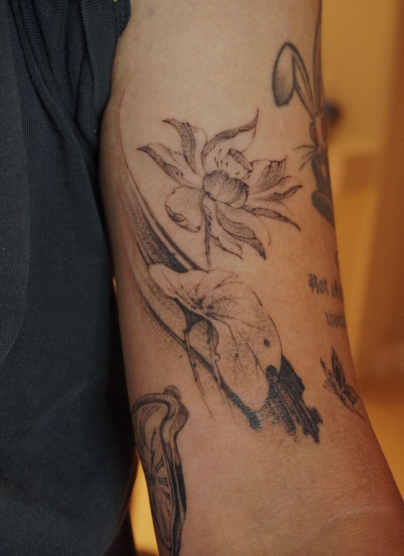 Fine-line botanical sketch tattoo with lily and leaf