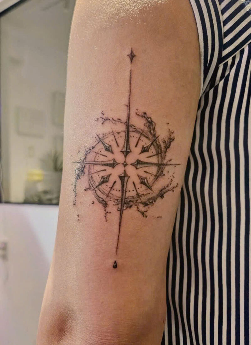 Fine-line compass rose tattoo with splash details