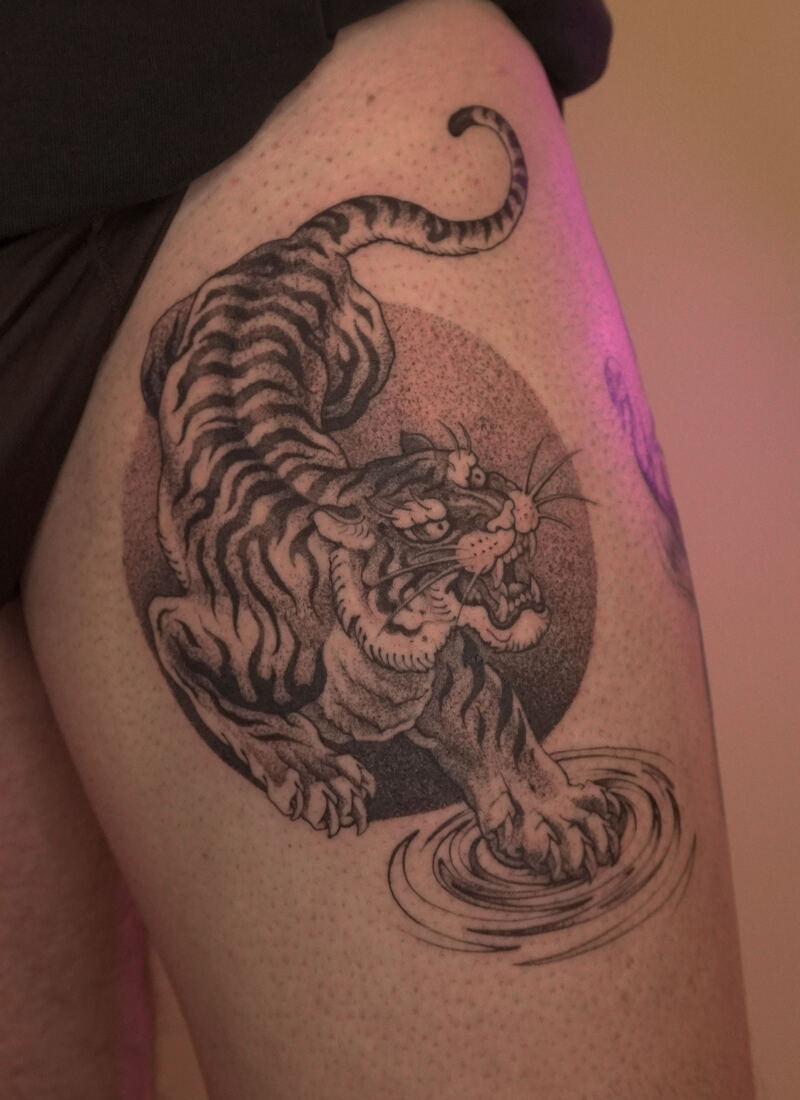 Japanese-style crouching tiger tattoo with sun and water ripples