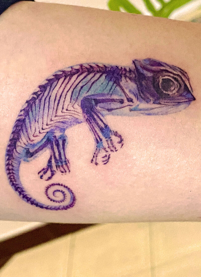Watercolor-style chameleon skeleton tattoo in purple and blue