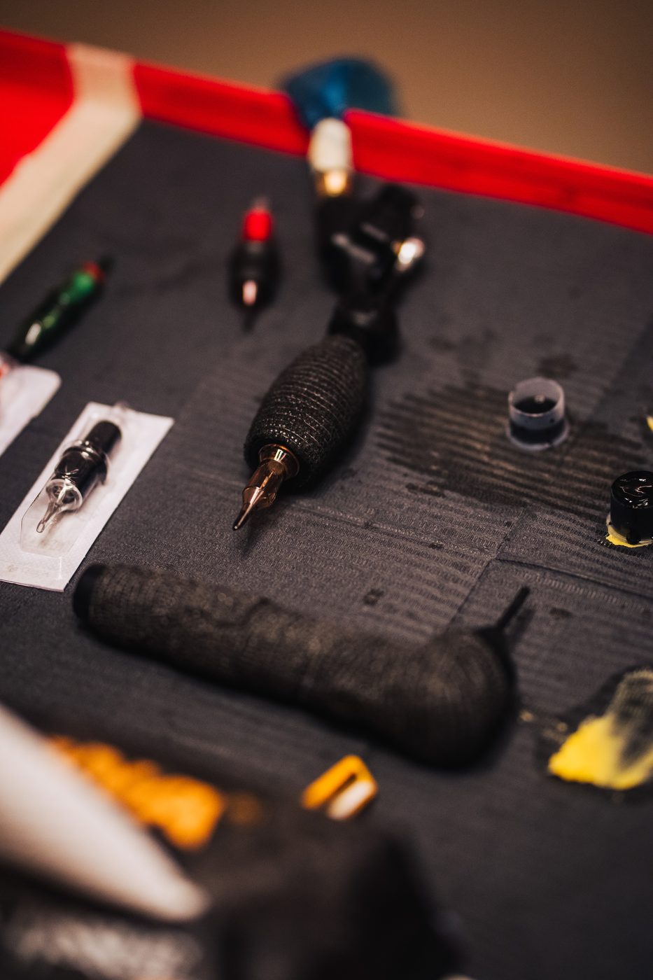 Tattoo machine, ink caps, and sterile needle cartridges laid out before a session