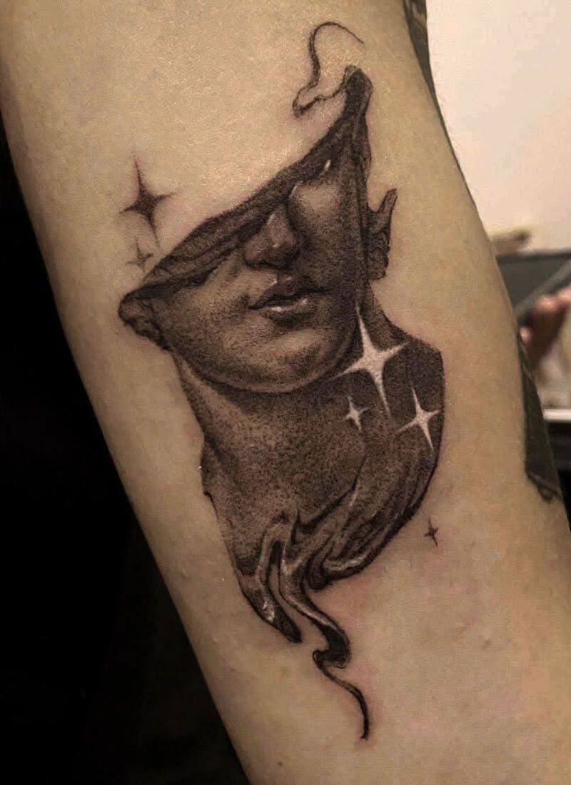 Dotwork tattoo of a torn theatre mask with sparkles